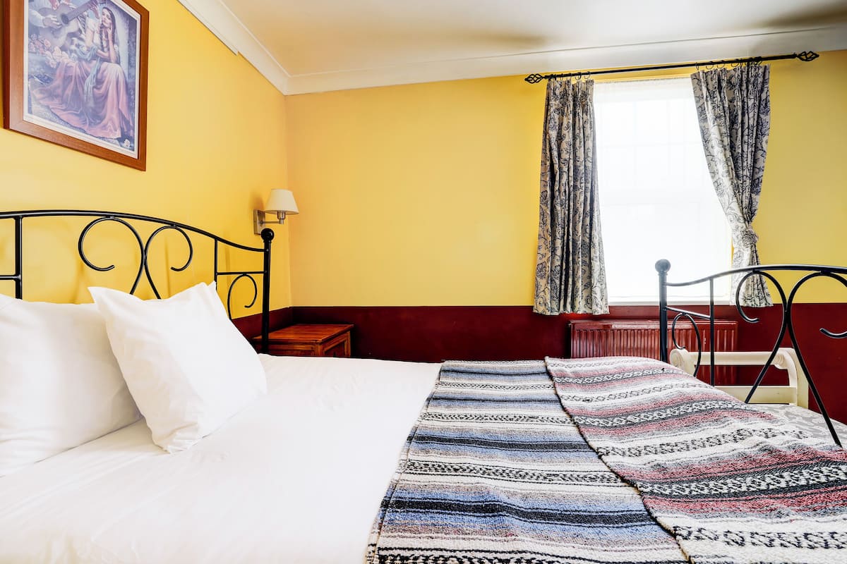 A bed with white linens, a patterned throw blanket, and a headboard.