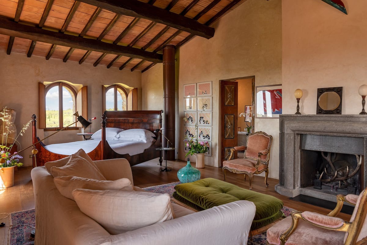 Una habitación amplia con una cama grande, una chimenea y una zona de estar acogedora.