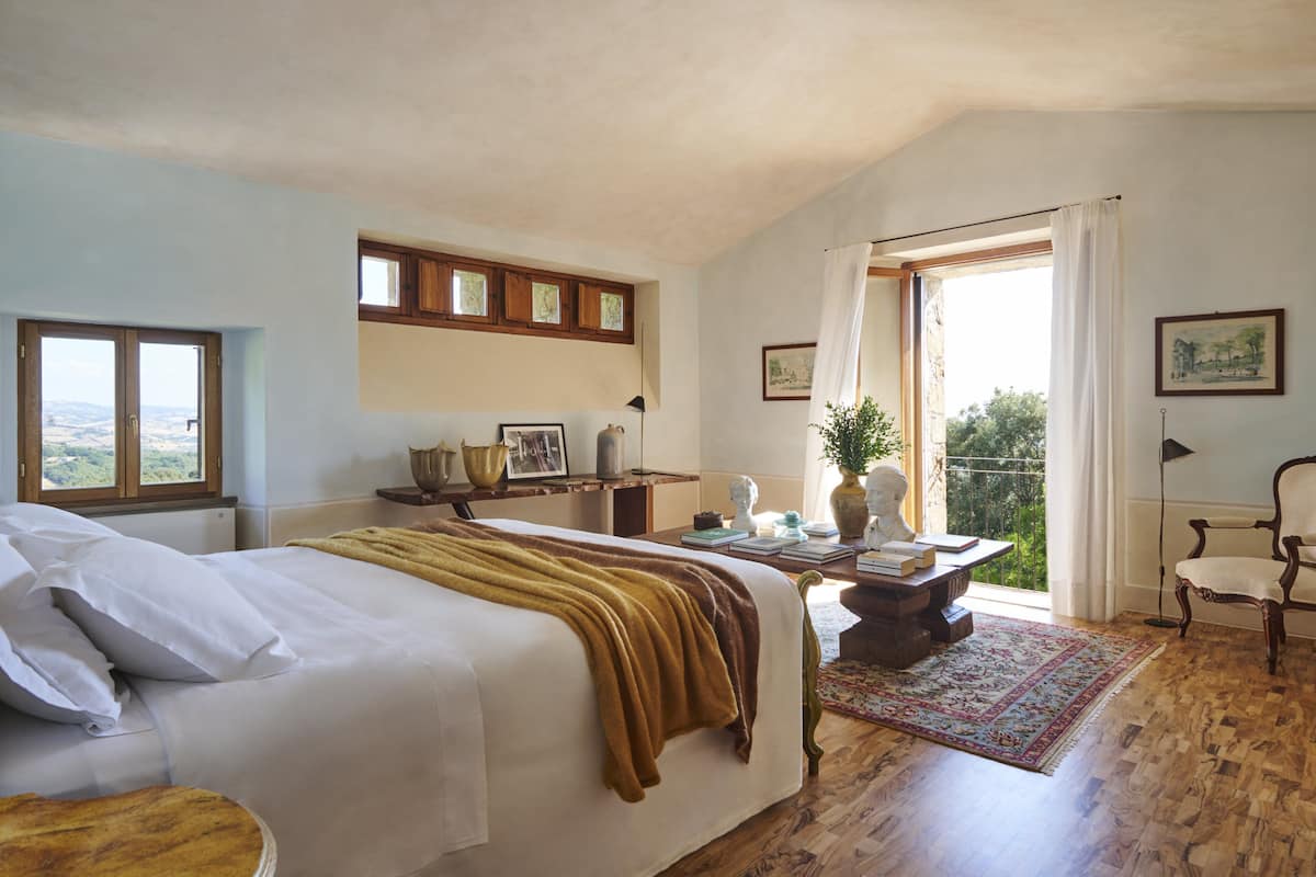 Un dormitorio con una cama grande, un escritorio, una silla y vistas al exterior.