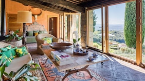 A cozy living room with a large wooden table, comfortable seating, and a view of the countryside. - Castello Di Vicarello (Cinigiano)