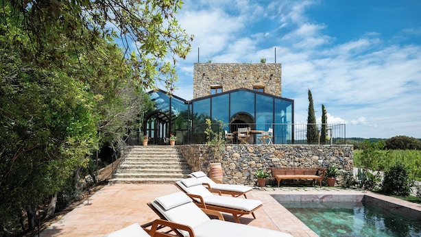 A modern house with a stone facade, a swimming pool, and outdoor seating. - Castello Di Vicarello (Cinigiano)