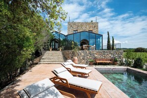 A modern house with a stone facade, a swimming pool, and outdoor seating. - Castello Di Vicarello (Cinigiano)
