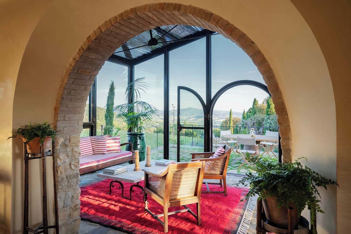 Un patio acogedor con alfombra roja, muebles de madera y plantas en macetas.