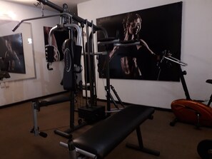 Een sportschool met trainingsapparatuur, een bank en een grote poster aan de muur.