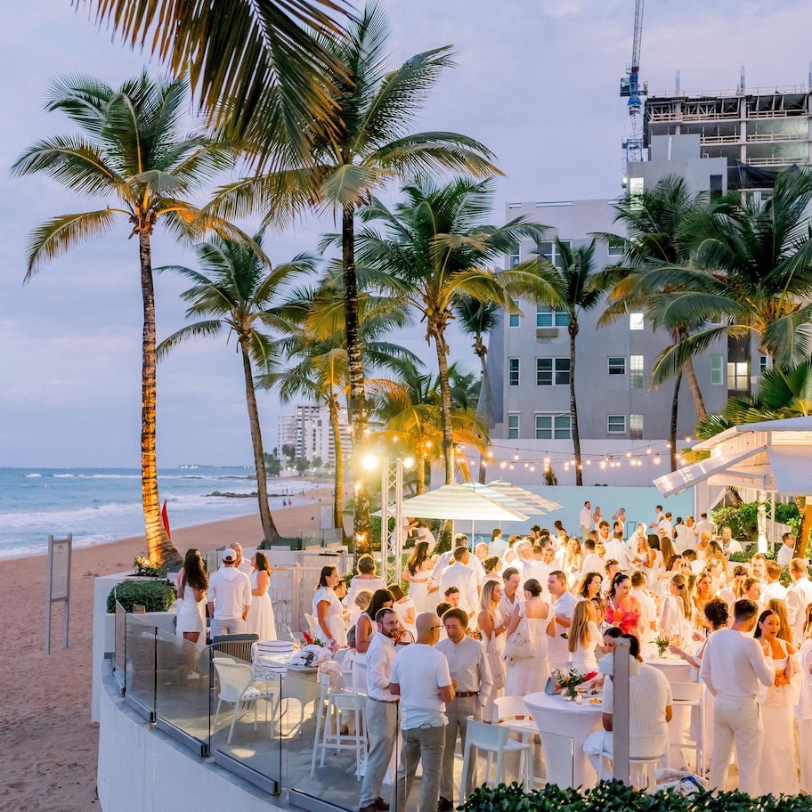 A beachside event with palm trees and a building in the background.