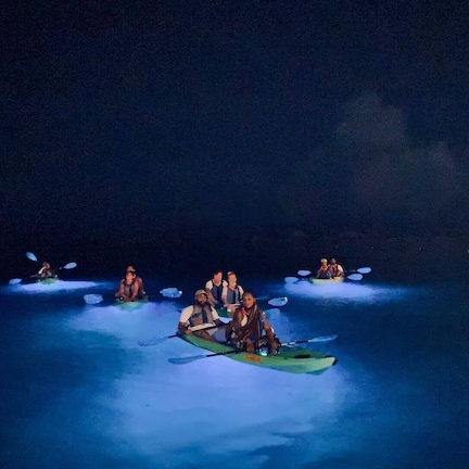 A group of people in kayaks on a body of water at night.