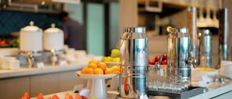 Montaje de bufé con diversos alimentos y dispensadores de bebidas.