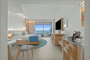 A modern hotel room with a bed, desk, chair, and a view of the ocean. - La Concha Resort, Puerto Rico, Autograph Collection (San Juan)