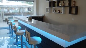 Una cocina moderna con barra, taburetes y estantes empotrados con botellas.
