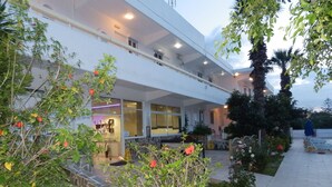 Un hotel con un espacio exterior cubierto, un restaurante y un jardín con diversas plantas y flores.