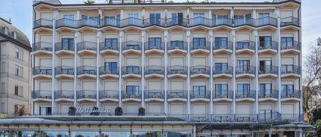 A multi-story hotel with balconies, a restaurant, and a fountain.