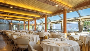 Un comedor amplio con mesas redondas, manteles blancos y sillas color beige.