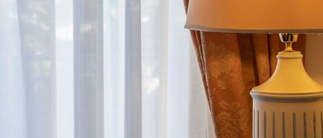 A lamp on a table with a window in the background.