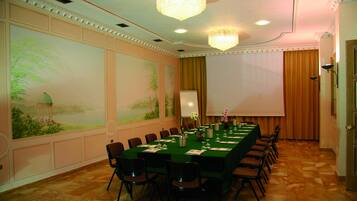 A conference room with a long table, chairs, a projector screen, and a large wall mural.