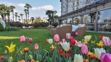 Un jardin où s’épanouissent de nombreuses variétés de tulipes, une pelouse verdoyante et, au fond, un bâtiment doté d’une façade en verre.