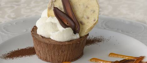 A dessert with whipped cream and chocolate pieces on a plate.