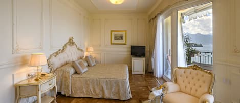 A luxurious bedroom with a large bed, a television, a chaise lounge, and a view of the sea.