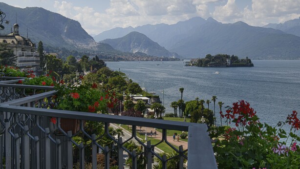 Vista de un lago con montañas, una pequeña isla y un edificio con cúpula.
