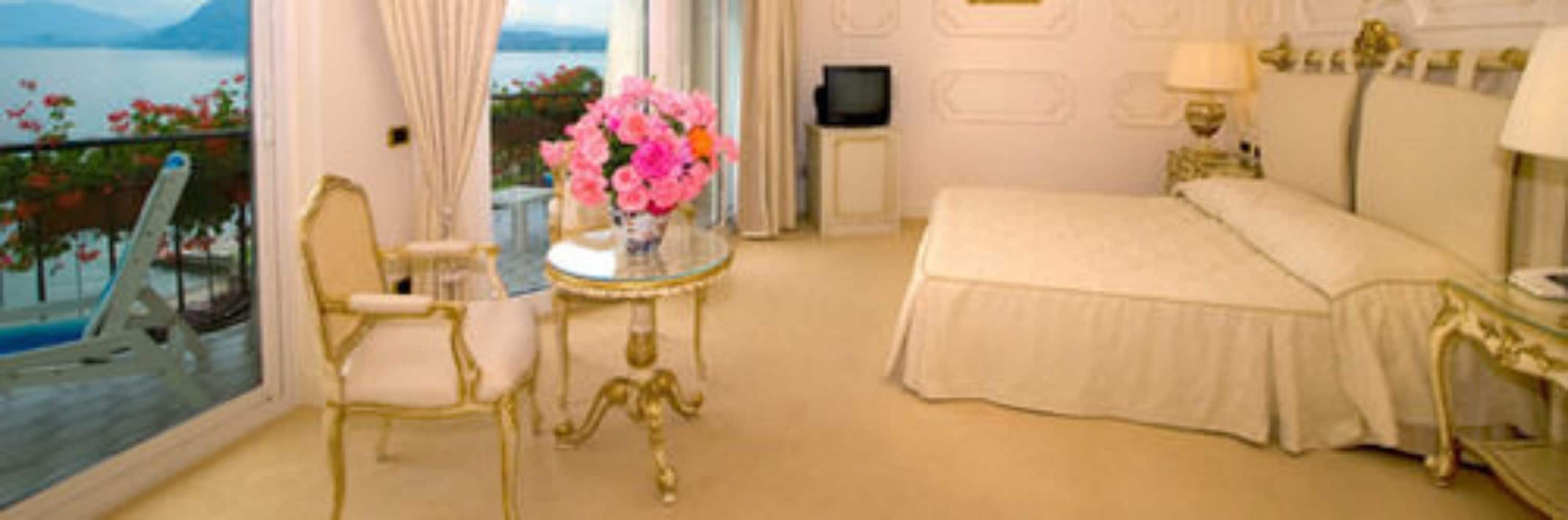 Un dormitorio lujoso con una cama grande, una zona de estar con una mesa y sillas, y vistas al mar.