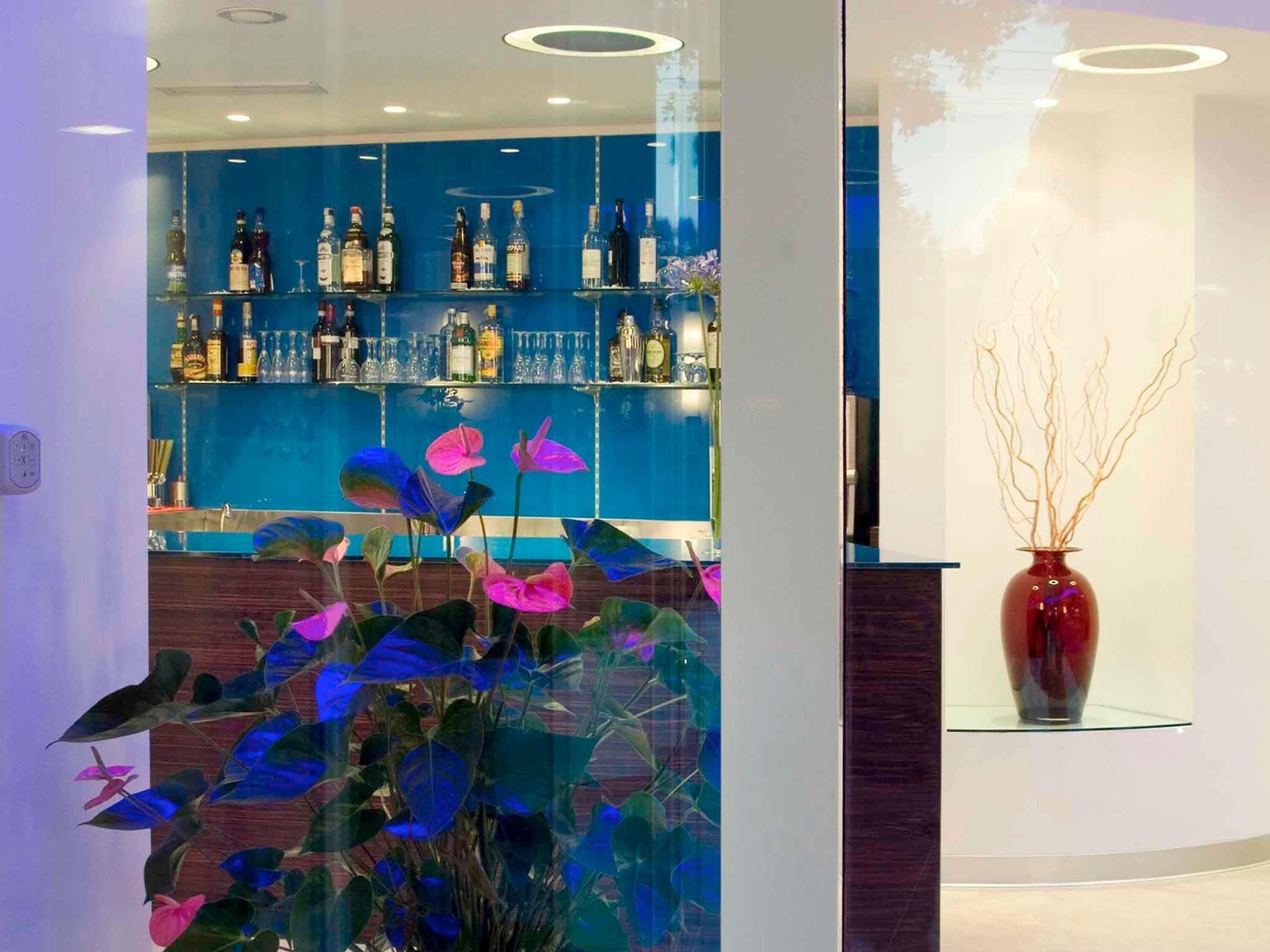 Un espace bar avec des étagères remplies de bouteilles et un vase décoratif orné de branches.