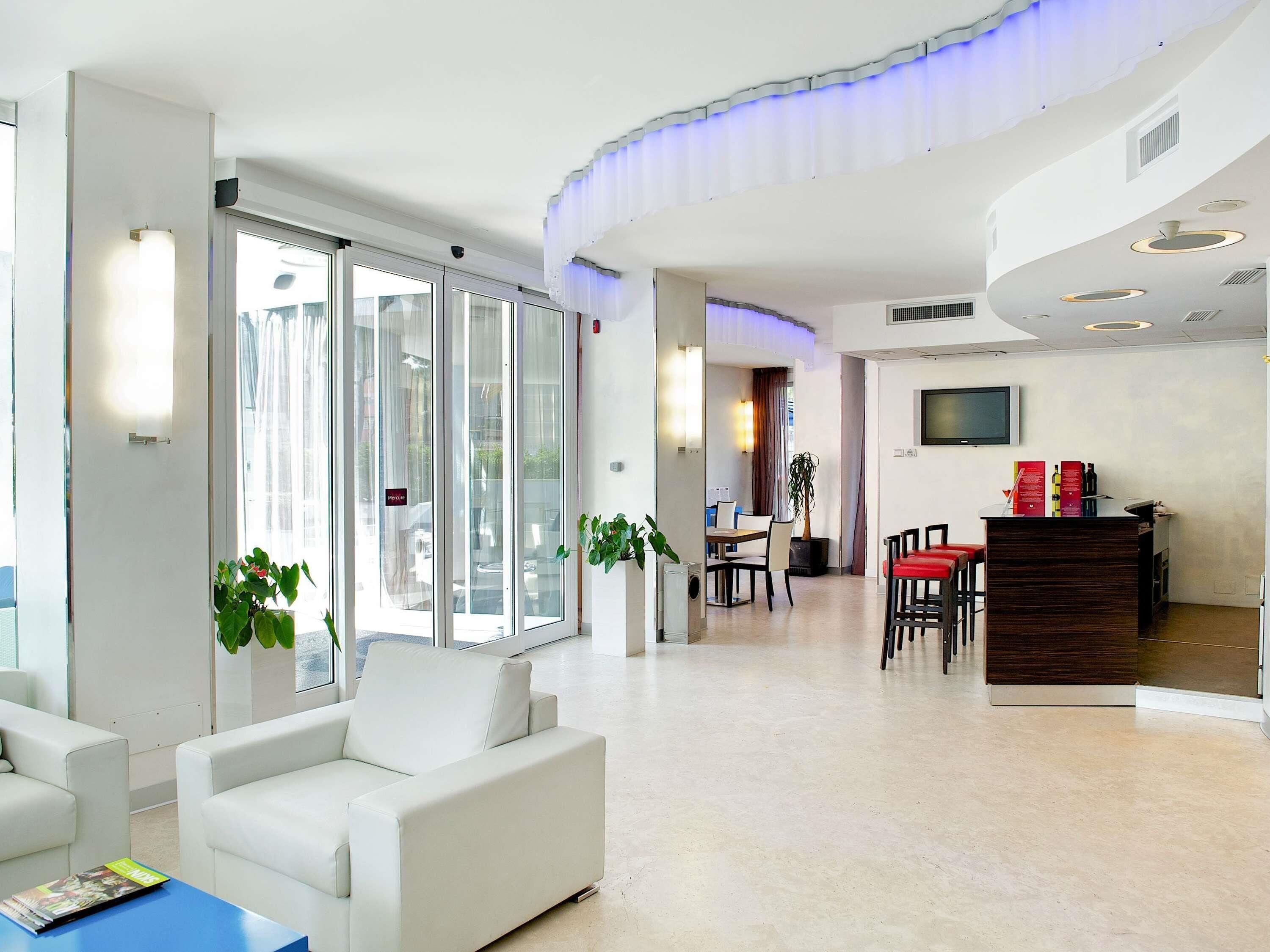 Un moderno vestíbulo de hotel con mostrador de recepción, zona de estar y grandes ventanales.