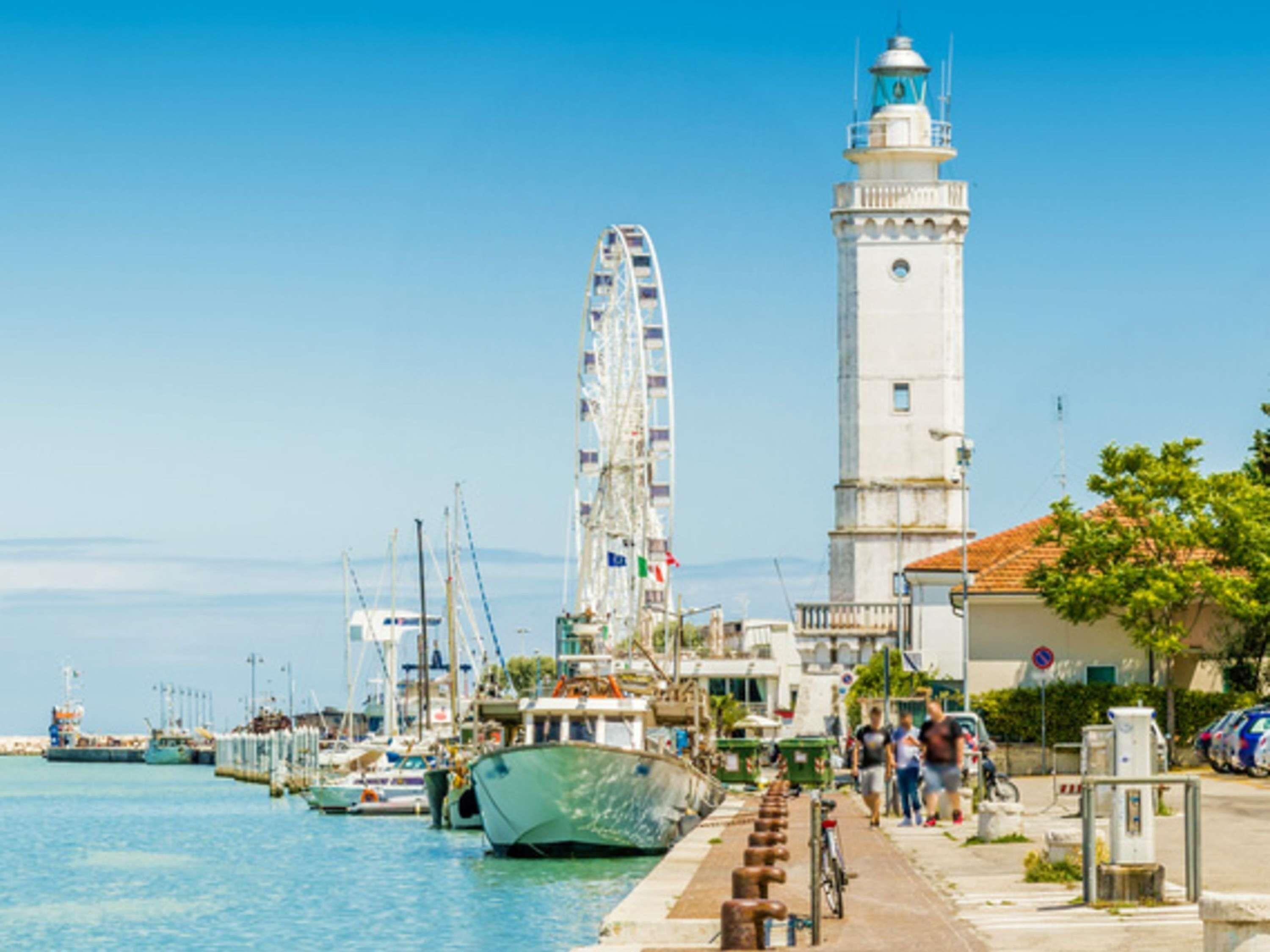 Ein Yachthafen mit Booten, einem Leuchtturm und einem Riesenrad.