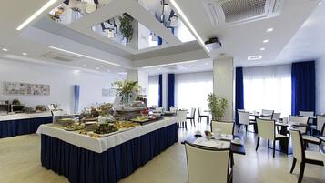 Un espace de restauration moderne dans un hôtel, avec un buffet, plusieurs tables et chaises.
