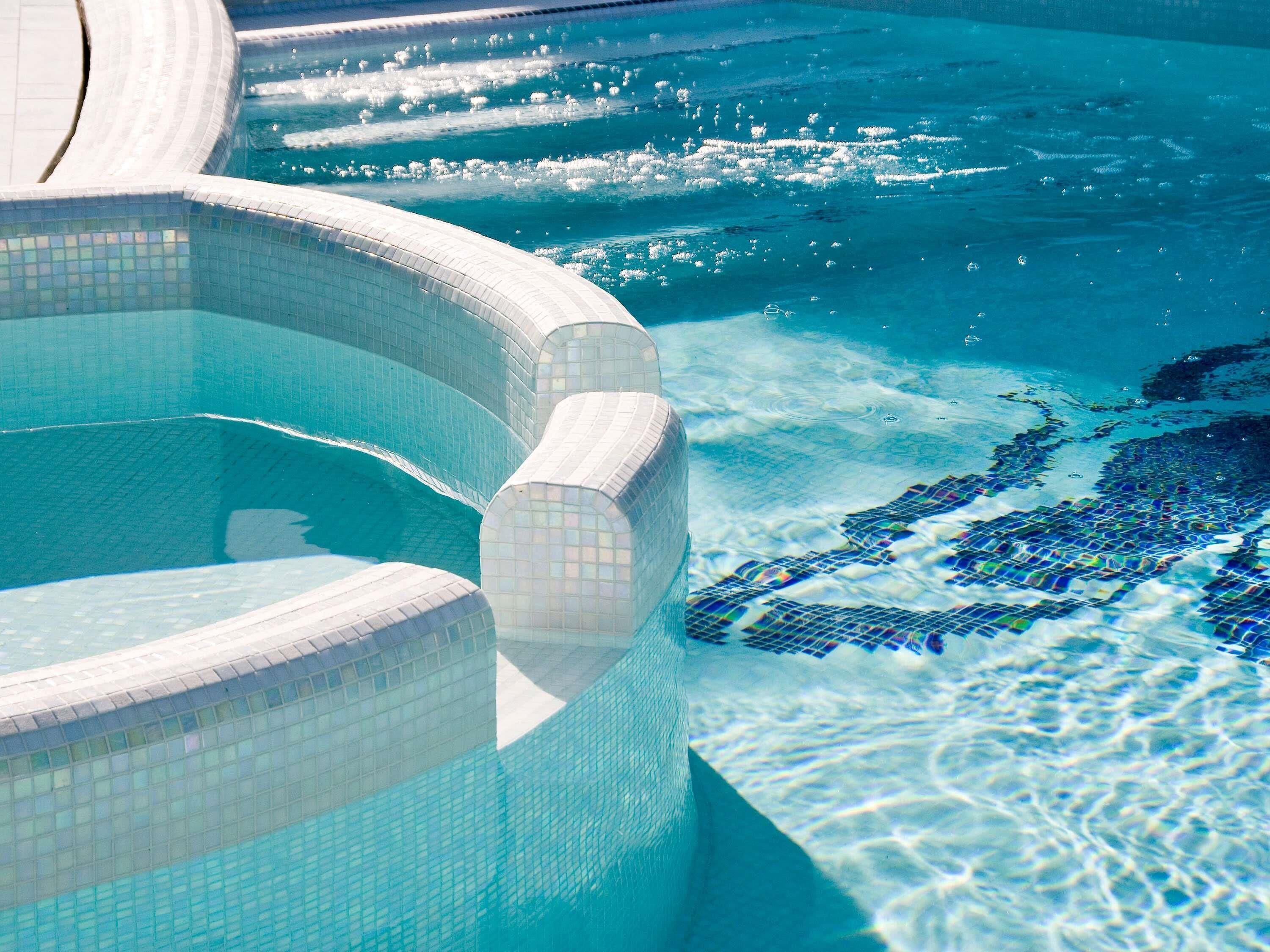 Una piscina con agua azul cristalina y bordes azulejados.