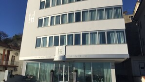 Een modern hotel met een witte gevel, meerdere verdiepingen en grote ramen.