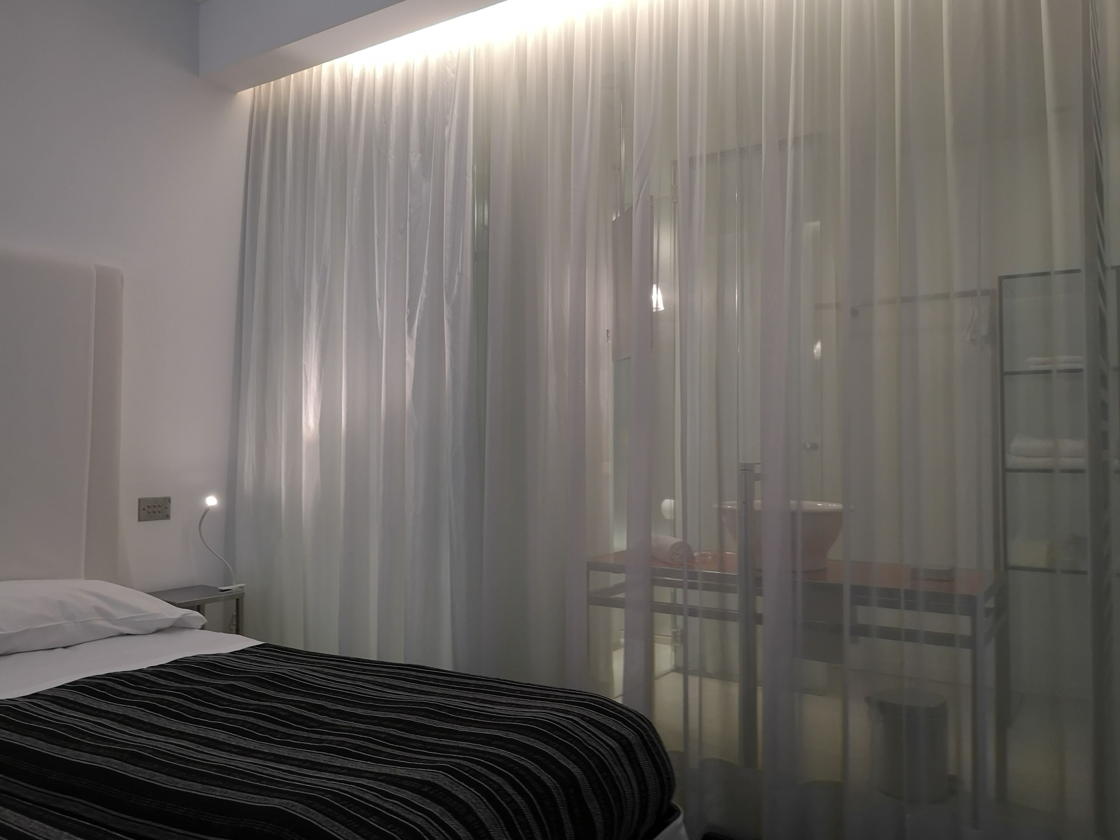 Quarto de hotel com uma cama, uma escrivaninha e uma cadeira.