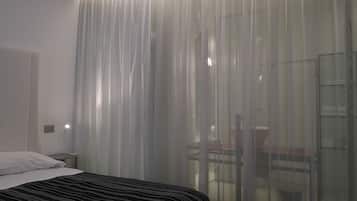 Quarto de hotel com uma cama, uma escrivaninha e uma cadeira.