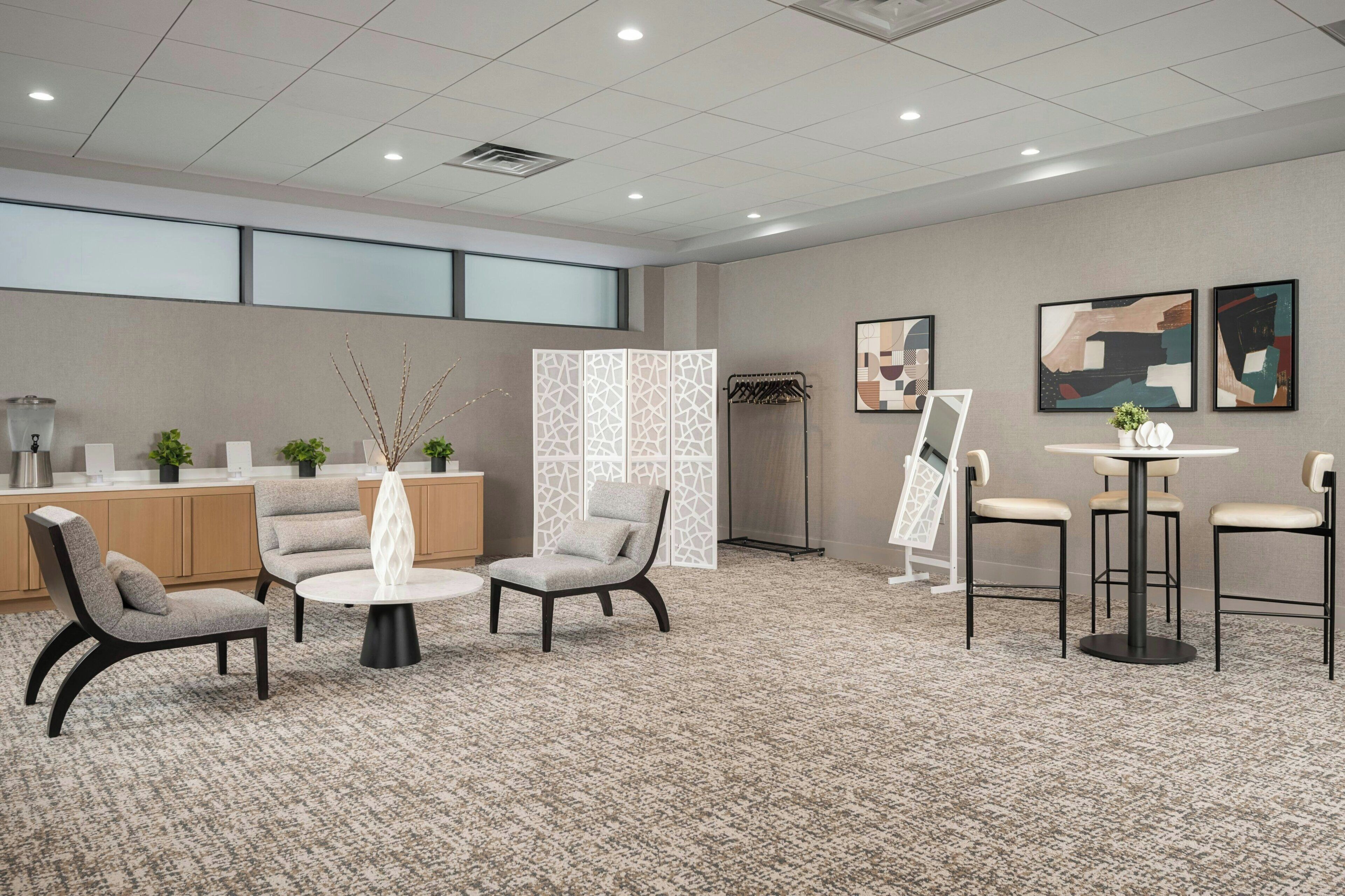 Een hotel lobby met zitplaatsen, een receptiebalie, kunstwerken en een decoratief scheidingswand.