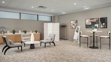Een hotel lobby met zitplaatsen, een receptiebalie, kunstwerken en een decoratief scheidingswand.