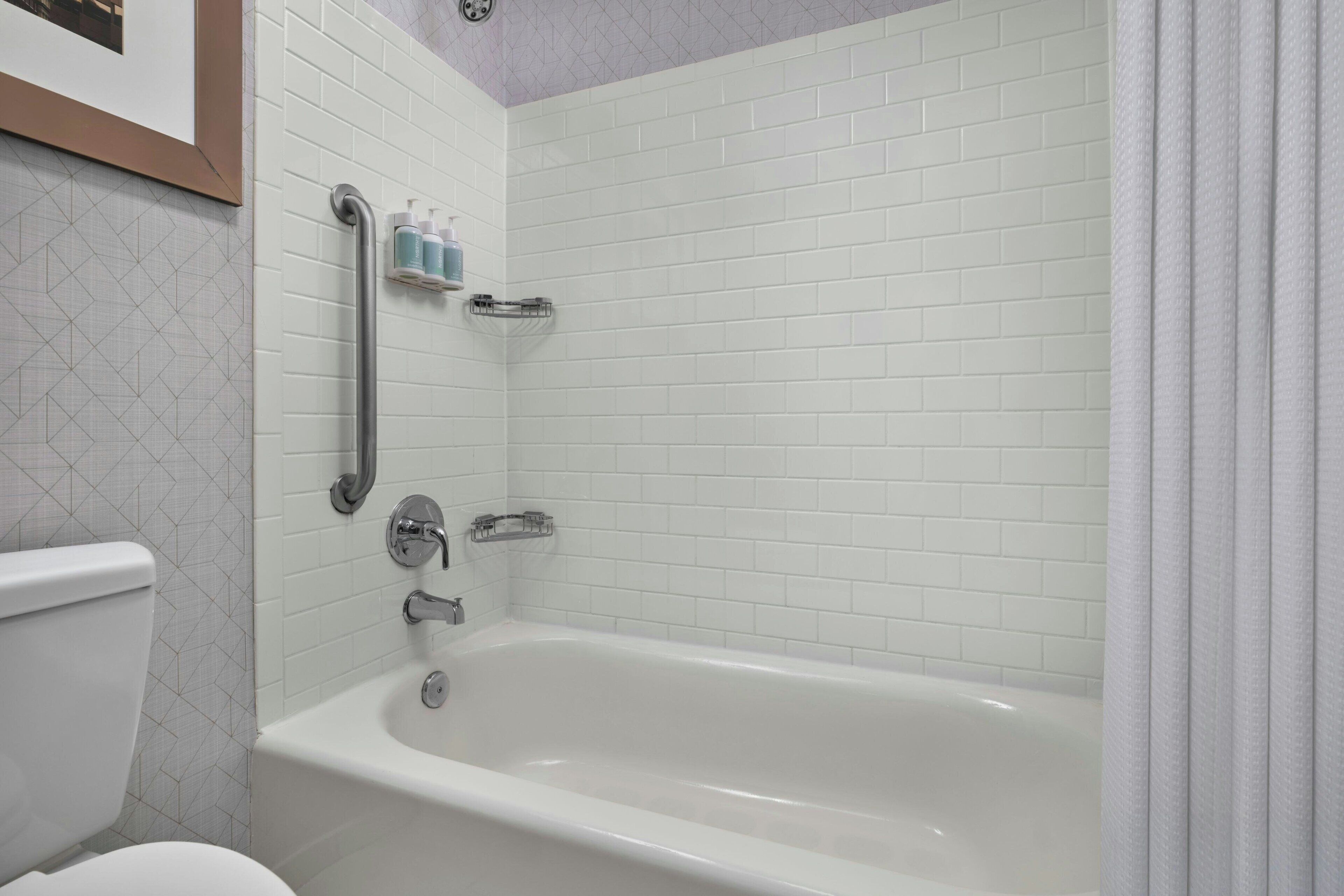 Une salle de bain avec une baignoire blanche, des toilettes et un espace douche.