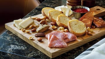Una tabla de madera con varios quesos, carnes y frutos secos sobre una encimera de mármol.