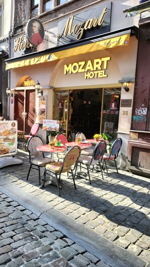 Un hôtel Mozart doté d’une terrasse, d’une enseigne représentant des gaufres et d’une enseigne ancienne au-dessus de l’entrée.