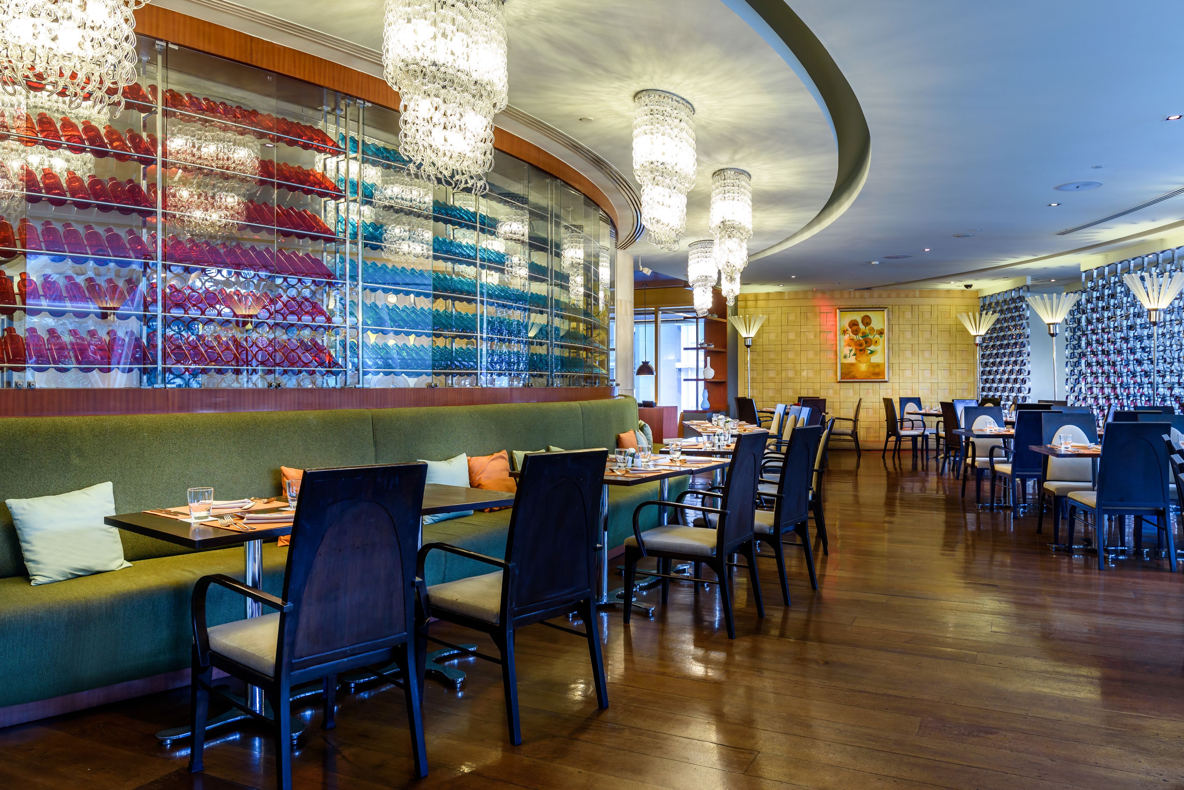 Ein Restaurant mit einer grünen Couch, schwarzen Stühlen und einer Wand voller farbenfroher Gläser.