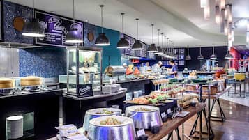 A buffet setup with various food stations, including a noodle section, and a counter where staff are serving.