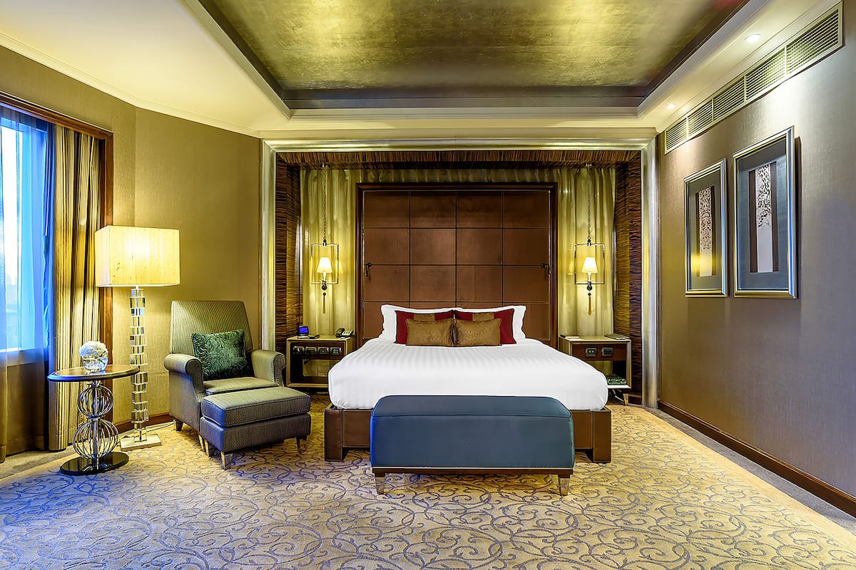 Een hotelkamer met een groot bed, een stoel, een tafeltje en een bank.