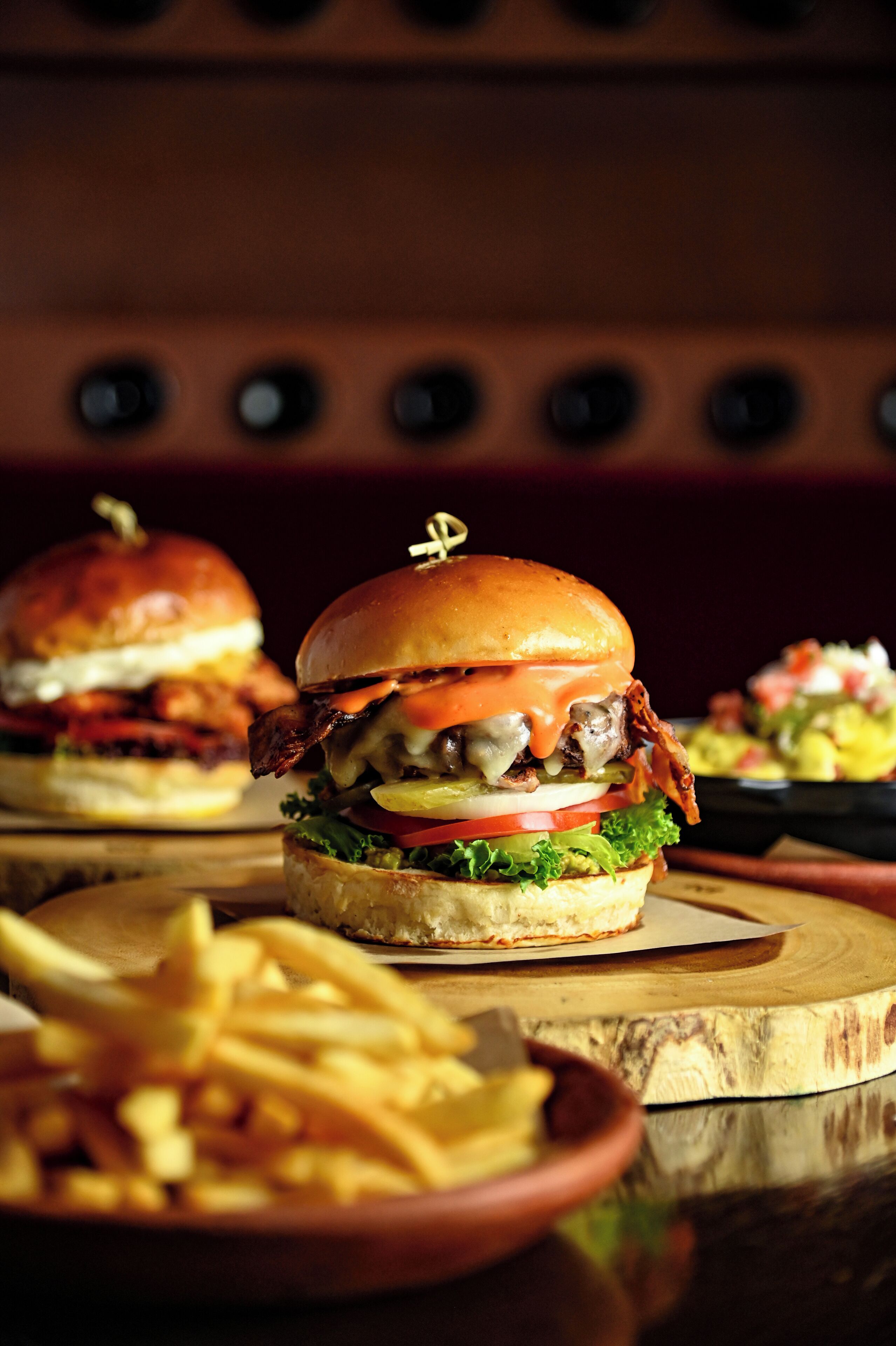 Una hamburguesa con lechuga, tomate y queso, acompañada de papas fritas y una ensalada.
