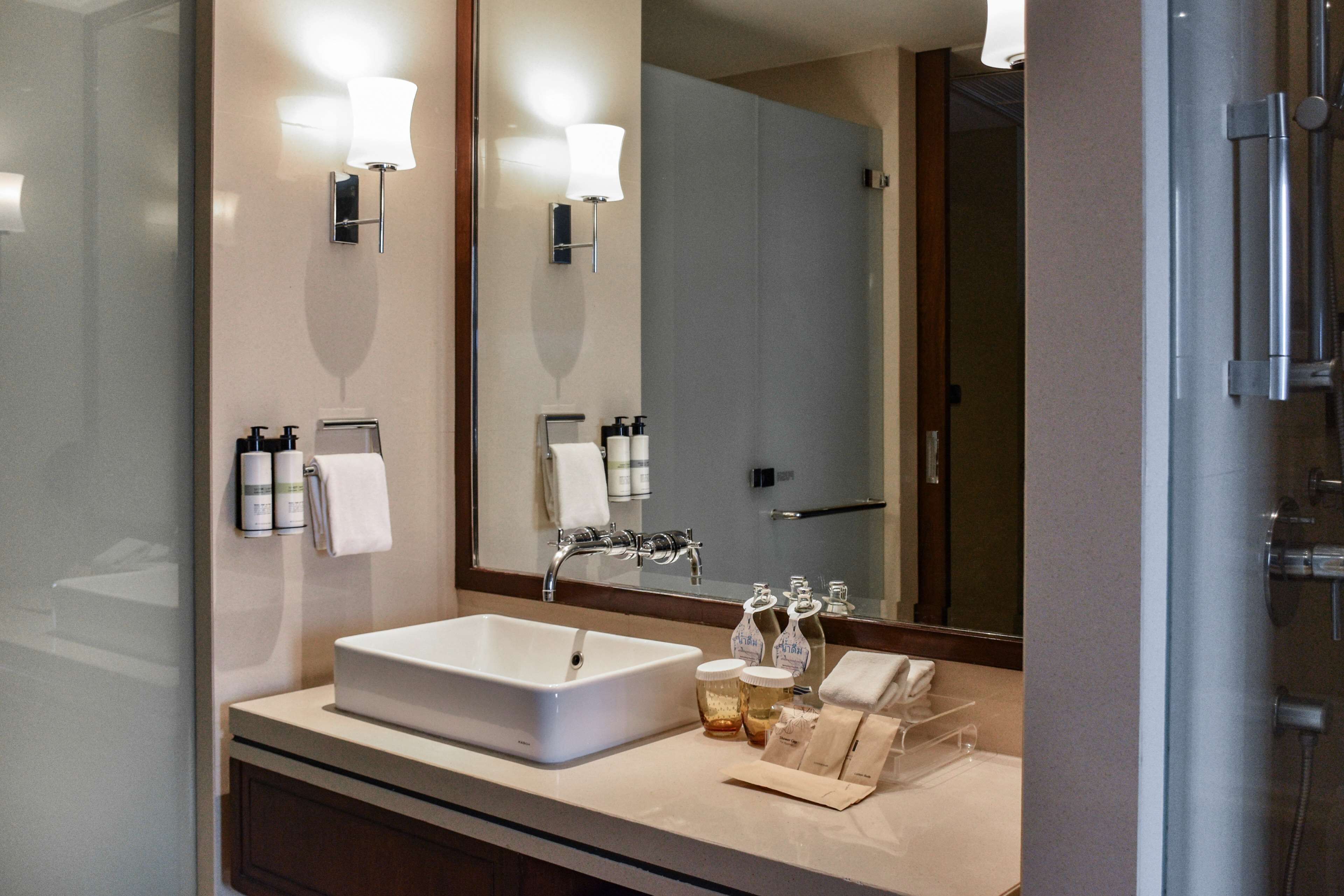 A modern bathroom with a large mirror, a white sink, and a shower.
