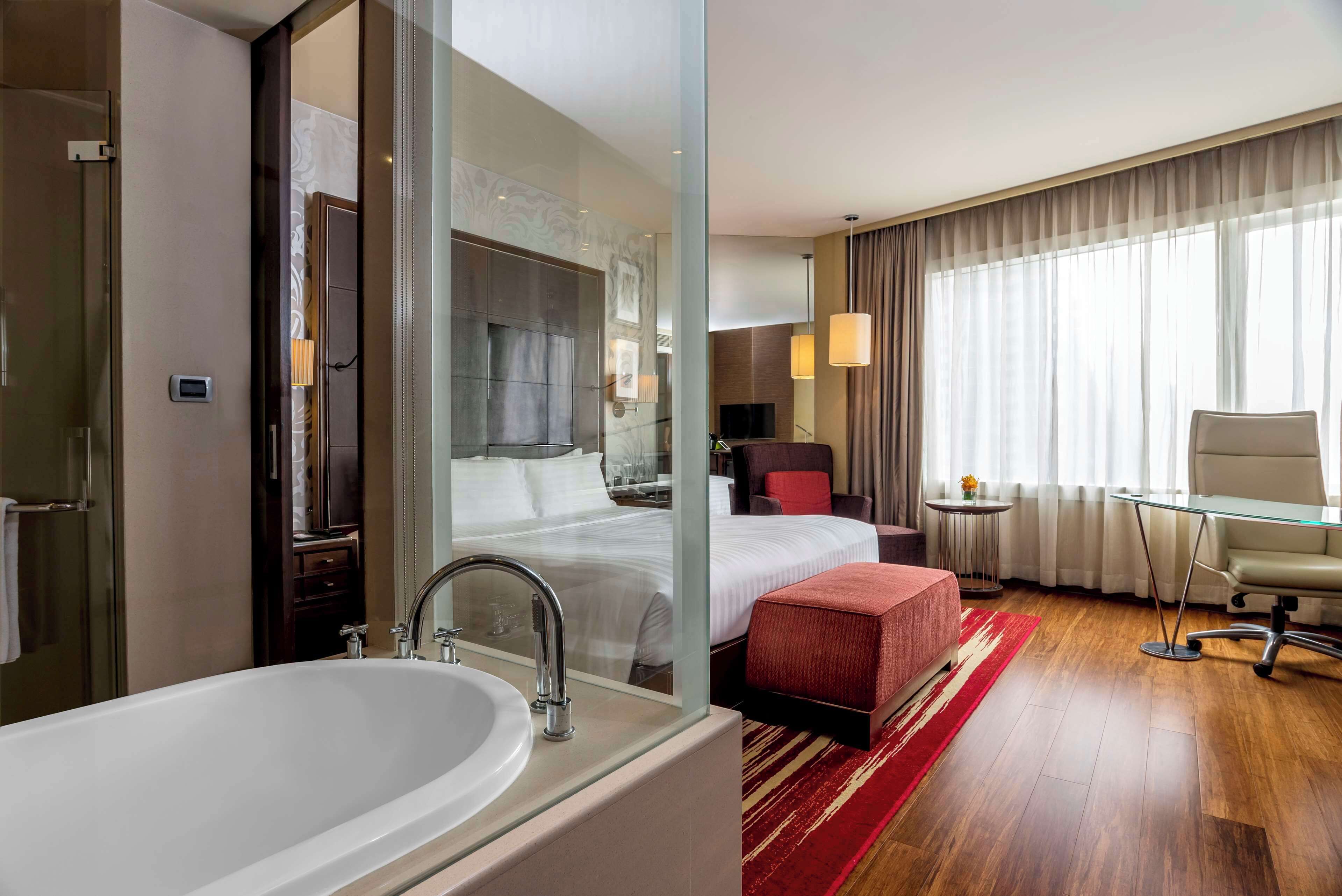 Habitación de hotel con baño amplio, cama, escritorio y silla.
