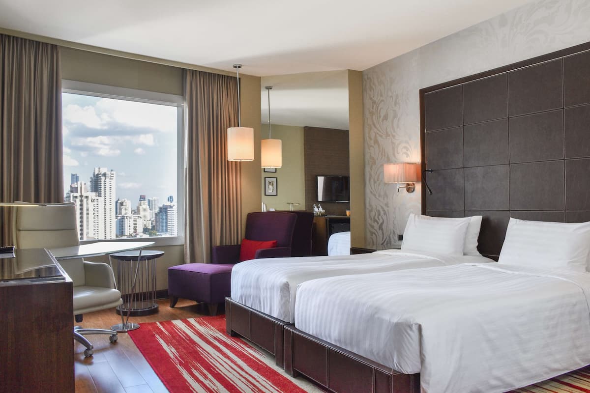 Een hotelkamer met een groot bed, een bureau, een stoel en uitzicht op de stad.