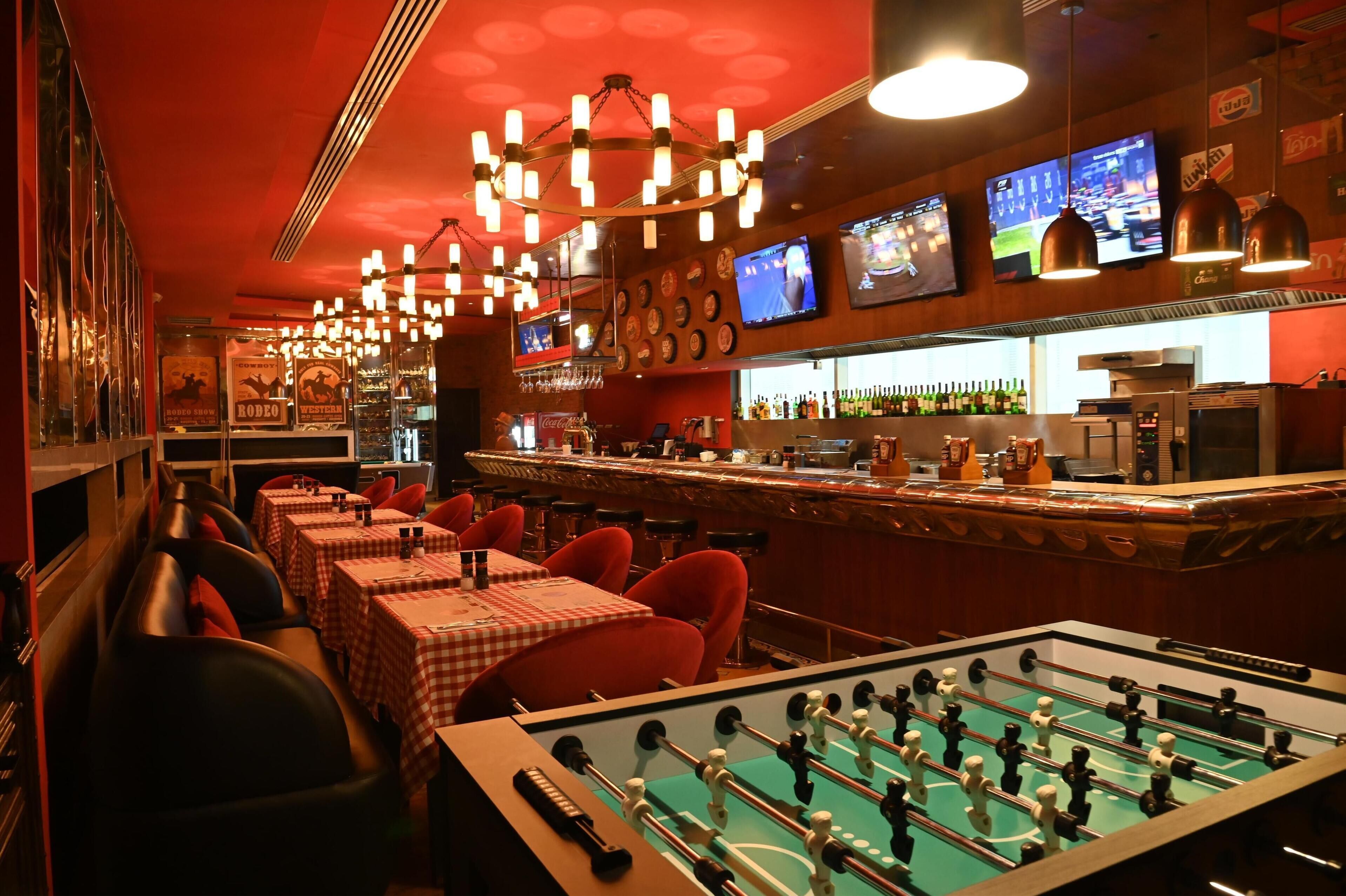 Un'area bar con tavoli, sedie e un tavolo da calcio.