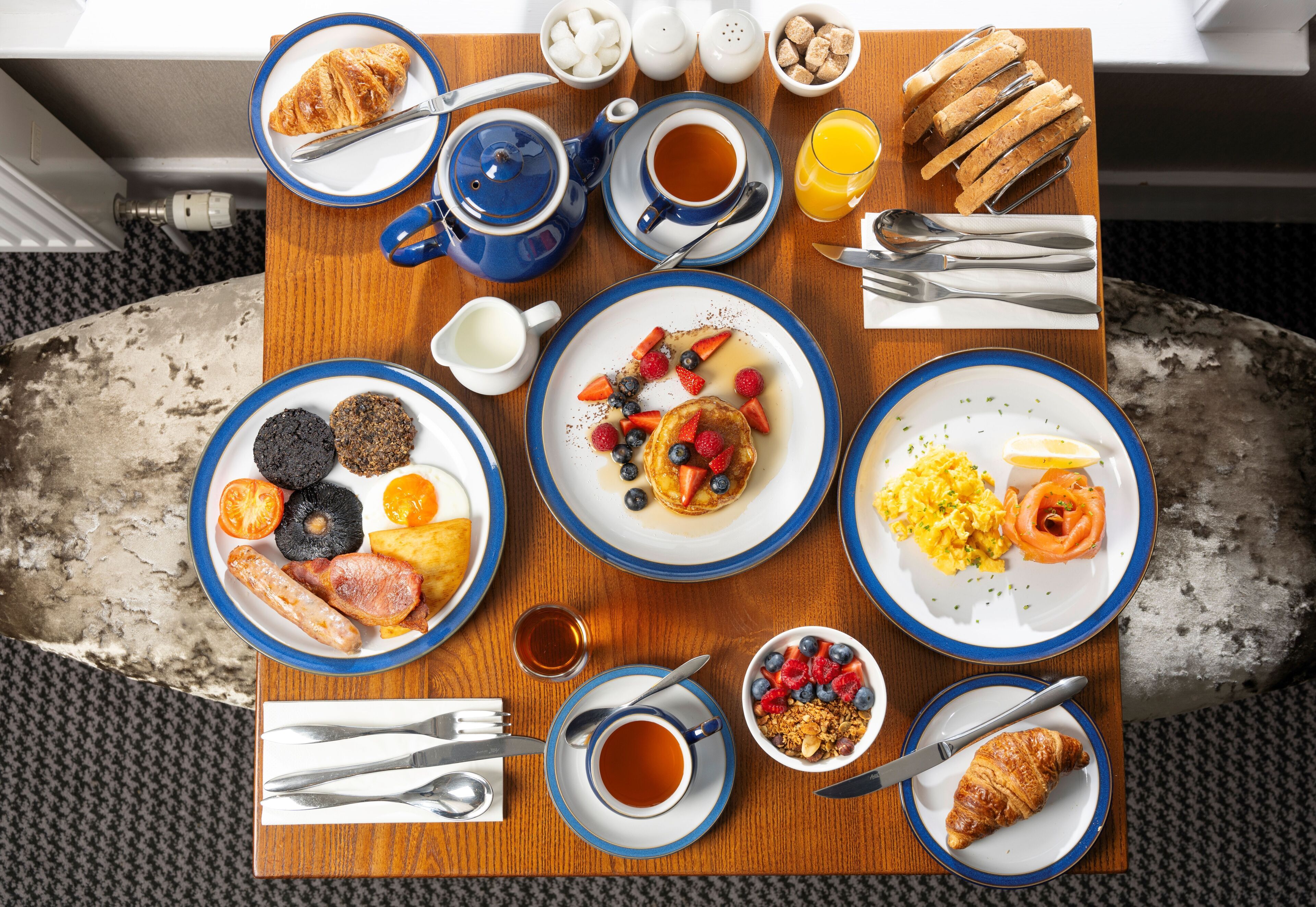 Ein Frühstücksbuffet mit verschiedenen Speisen, darunter Gebäck, Früchte und Rührei.