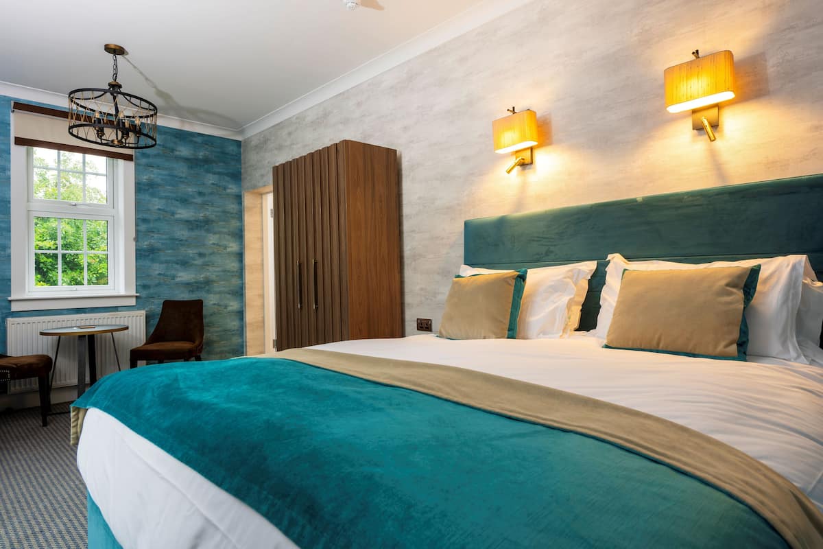 Ein Hotelzimmer mit einem großen Bett, einem Schreibtisch, einem Stuhl und einem Kleiderschrank.