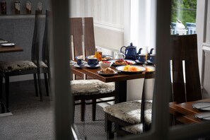 A dining area with a table set for breakfast, including plates of food, cups, and a teapot. - Toravaig House Hotel (Sleat)