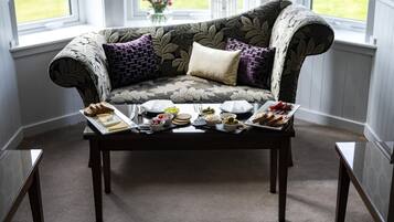 A cozy seating area with a sofa and a coffee table set with various food items.