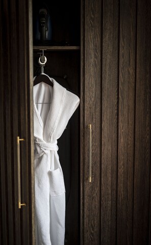 A wooden wardrobe with a white robe hanging on a hook. - Toravaig House Hotel (Sleat)