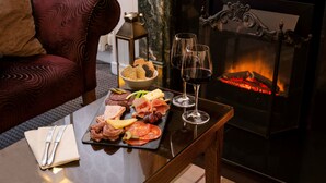 A dining table with a charcuterie board, wine glasses, and a fireplace in the background. - Toravaig House Hotel (Sleat)